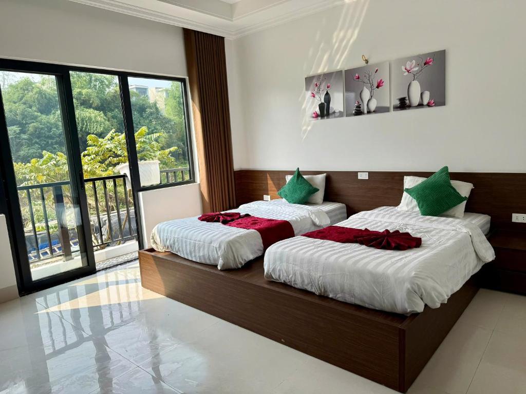 a bedroom with two beds and a large window at De' Mon Villa in Làng Tong Tchoung
