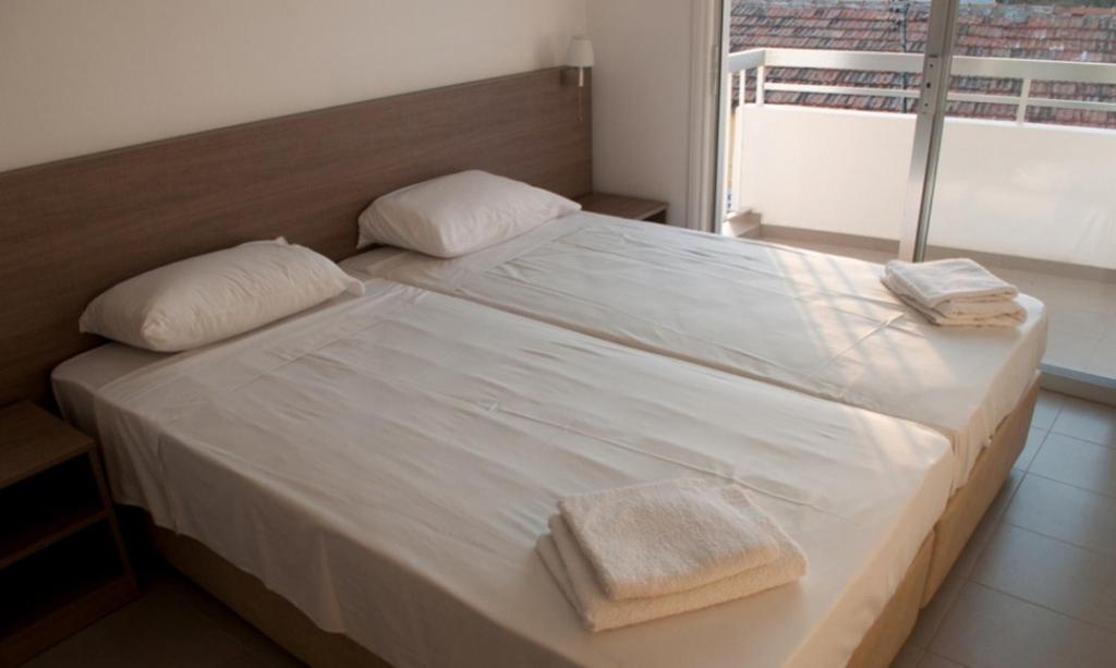 ein großes weißes Bett mit zwei Handtüchern darauf in der Unterkunft St. George Rent Rooms in Larnaka
