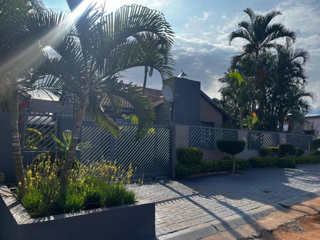 a fence with palm trees in front of a house at Guesthouse at 543 in Lebowakgomo