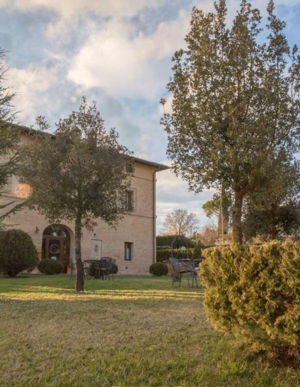 a building with two trees and a bench in a yard at B&B Fonte dei Tufi in Siena