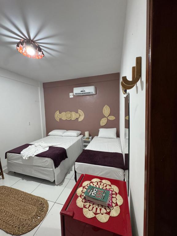 a bedroom with two beds and a table with a controller on it at Professor Guest House in Santo Amaro