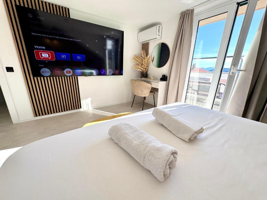 a bedroom with a white bed with a flat screen tv at Apartment Anchor Luxury in Slatine
