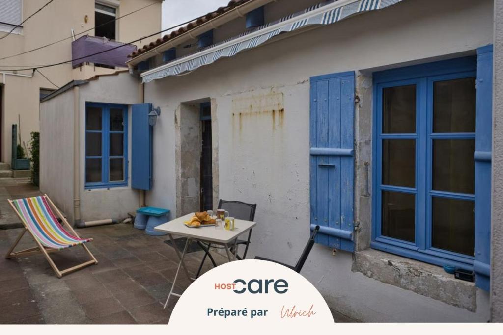 a table and chairs in front of a building with blue windows at Le refuge de la Fée - centre et plage in Fouras