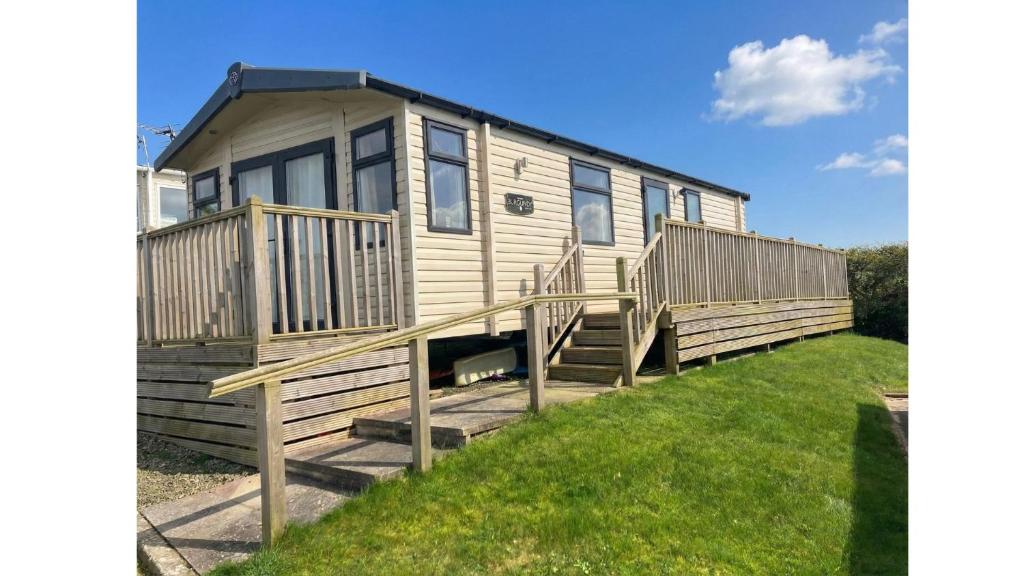 a mobile home with a deck and grass at Sunset Bay Aberaeron in Aberaeron