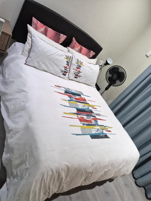 a bed with a white comforter with colorful pillows at Blouberg Guest suite, 3 km to the beach, Wi-Fi inc in Parklands