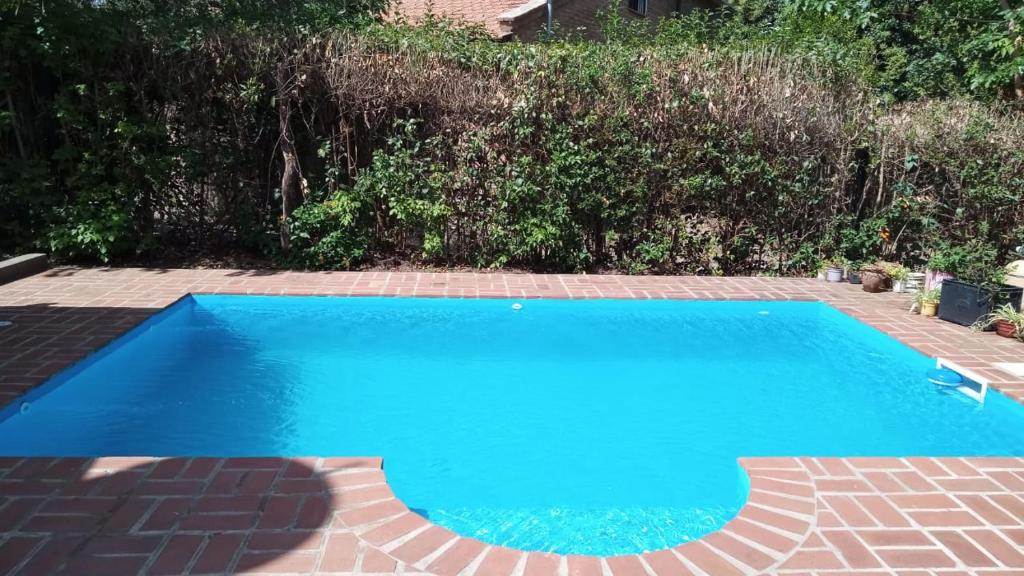 a blue swimming pool with a brick patio at casitadearminda-II in Villa Las Rosas