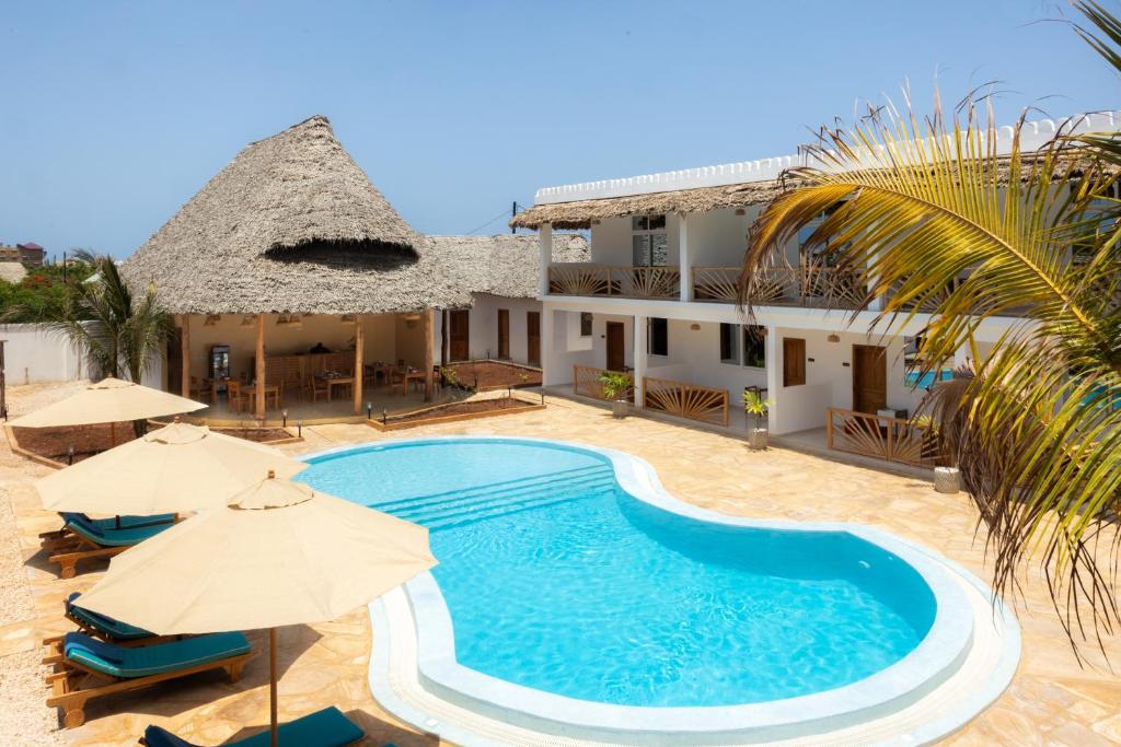 a pool in front of a house with umbrellas at OMNYA Nungwi Boutique Hotel in Nungwi