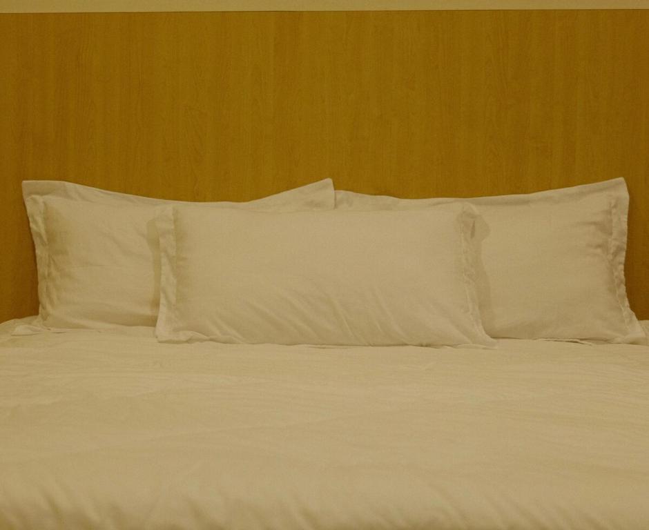a bed with white pillows on top of it at UrbaNest in Kota Bharu