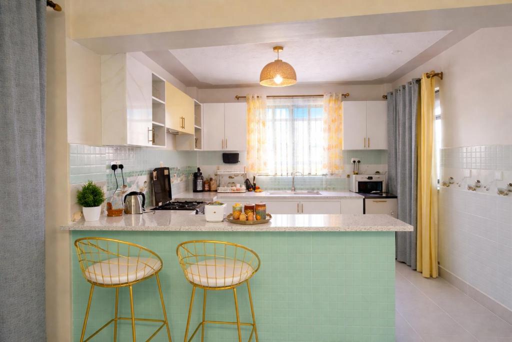 a kitchen with two bar stools at a counter at GLOW Suites in Naivasha