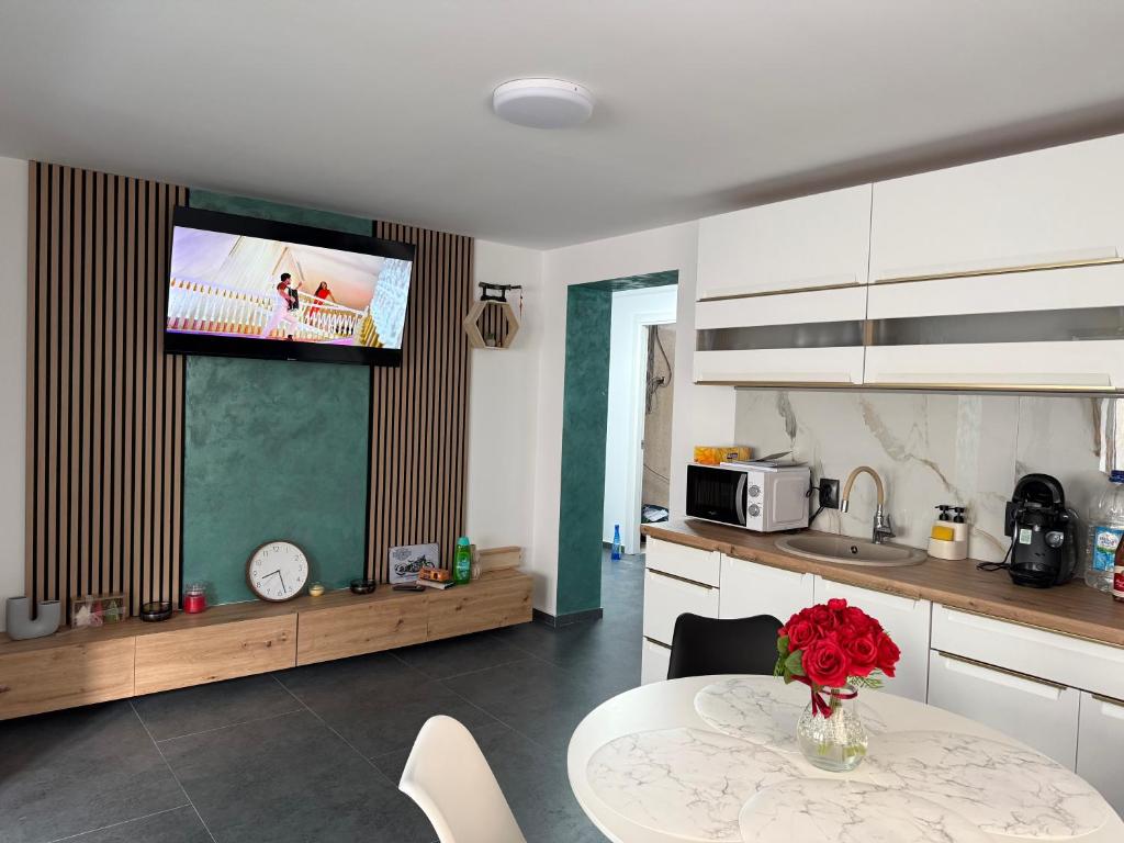 a kitchen with a table and a tv on the wall at Casa Apartament Refugiul Dornean in Vatra Dornei