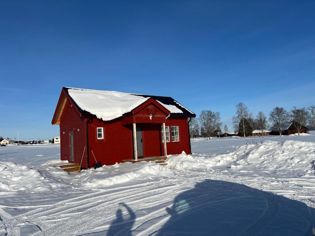 a red house with snow on the roof in the snow at Hjortgården in Mora