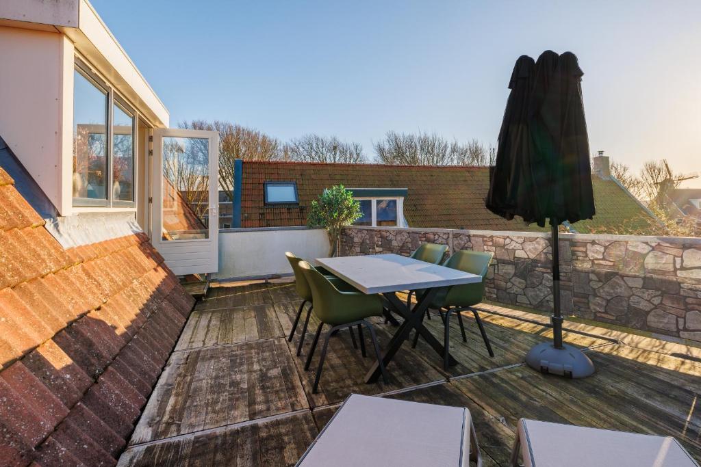 a patio with a table and chairs and an umbrella at Zilt in Hollum