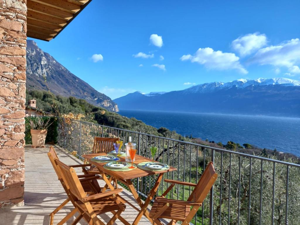 a table and chairs on a balcony with a view of the water at Casa del Codirosso in Gargnano
