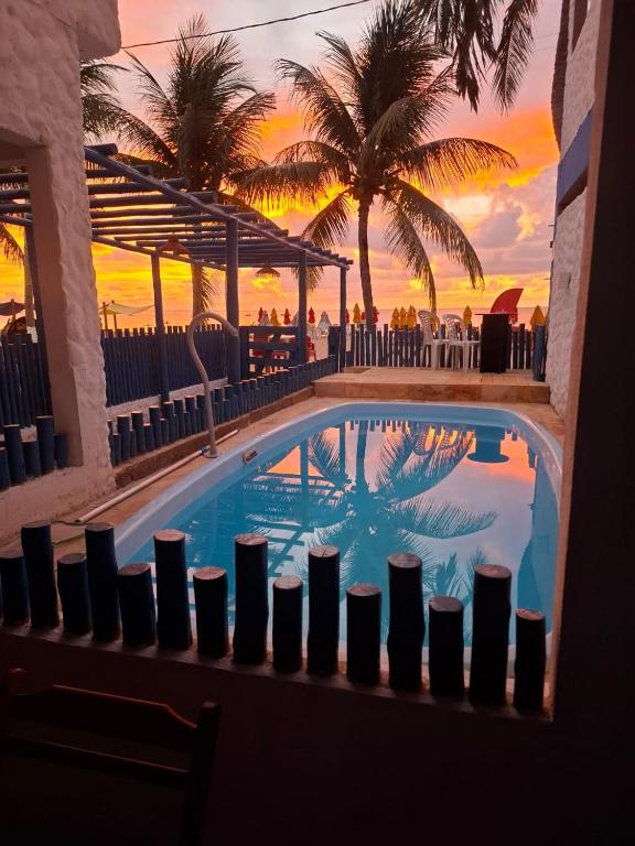 a swimming pool with a sunset in the background at Pousada Pé no Mar in Japaratinga