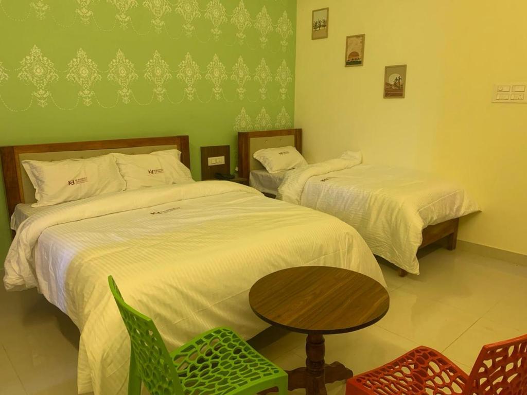 two beds in a room with a table and chairs at KH Residency And Lodging in Punganūru