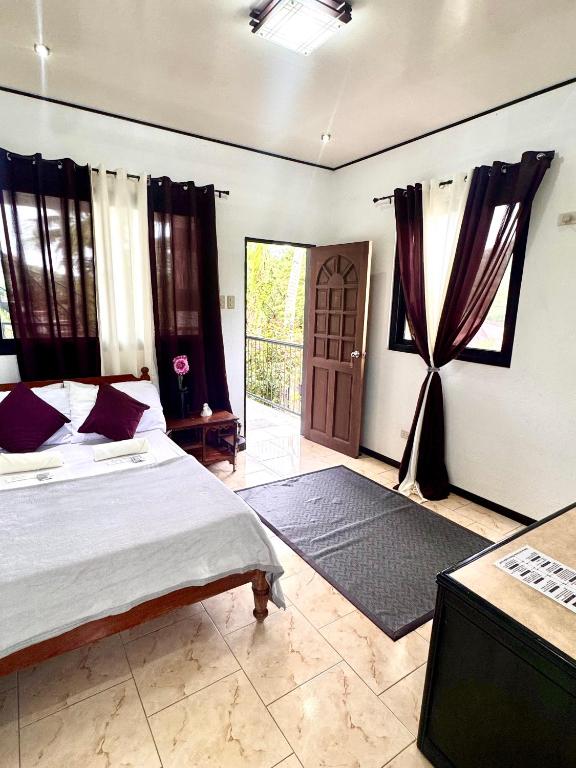 a bedroom with a bed and a television and a door at Placido's Vacation Home in Puerto Galera