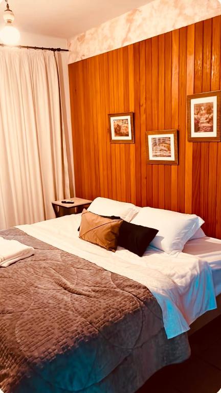a bedroom with a large bed with wooden walls at Refúgio do Ipê Rosa in Tubarão