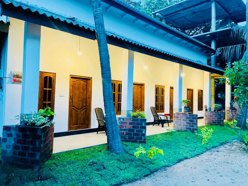 a house with chairs and a table in the yard at OM Inn in Trincomalee