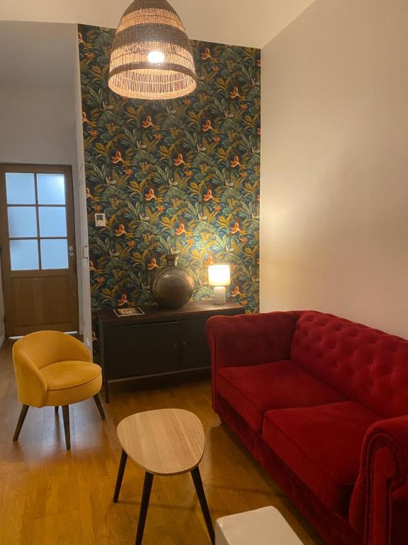 a living room with a red couch and a painting at La charmante petite maison in Croix