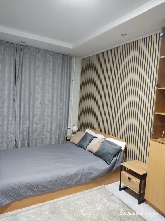 a bedroom with a bed and a large window at Бухар жырау 45 in Karagandy