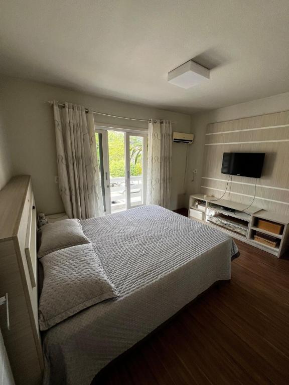 a bedroom with a bed and a sliding glass door at Casa com churrasqueira e ar para até 8 pessoas in Guabiruba