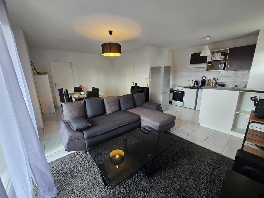 a living room with a couch and a table at T2 Confort - Clim, Piscine & Parking privé in Montauban