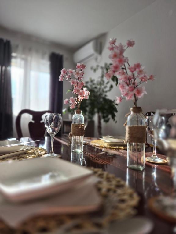 a table with plates and vases with pink flowers on it at Stan Duo in Herceg-Novi