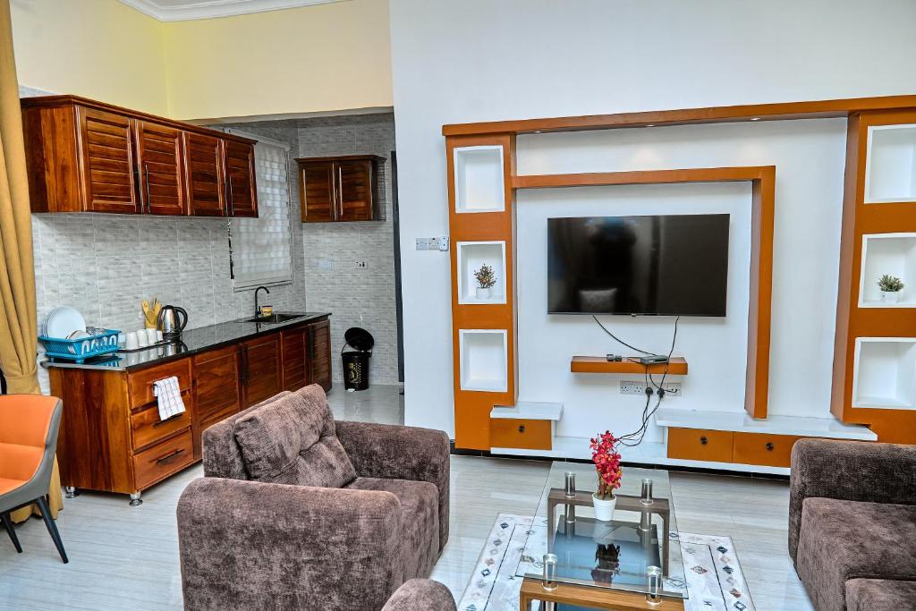 a living room with two chairs and a flat screen tv at Ngao Apartment and Suites Dodoma in Dodoma