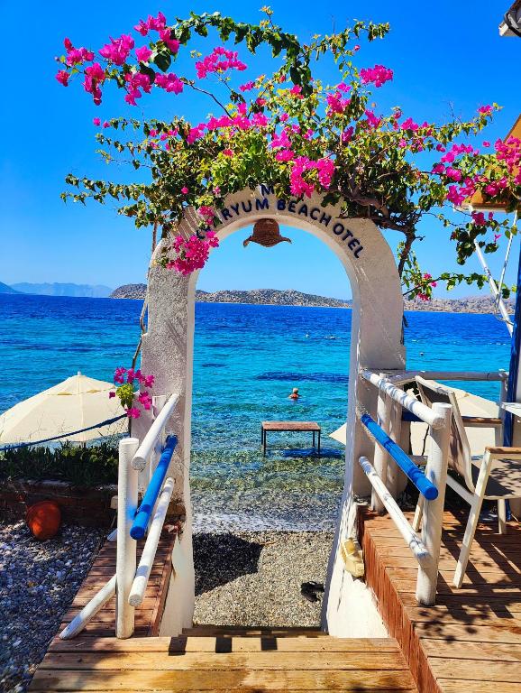 an archway with pink flowers on a beach at Mavi Akvaryum Pension in Sogut