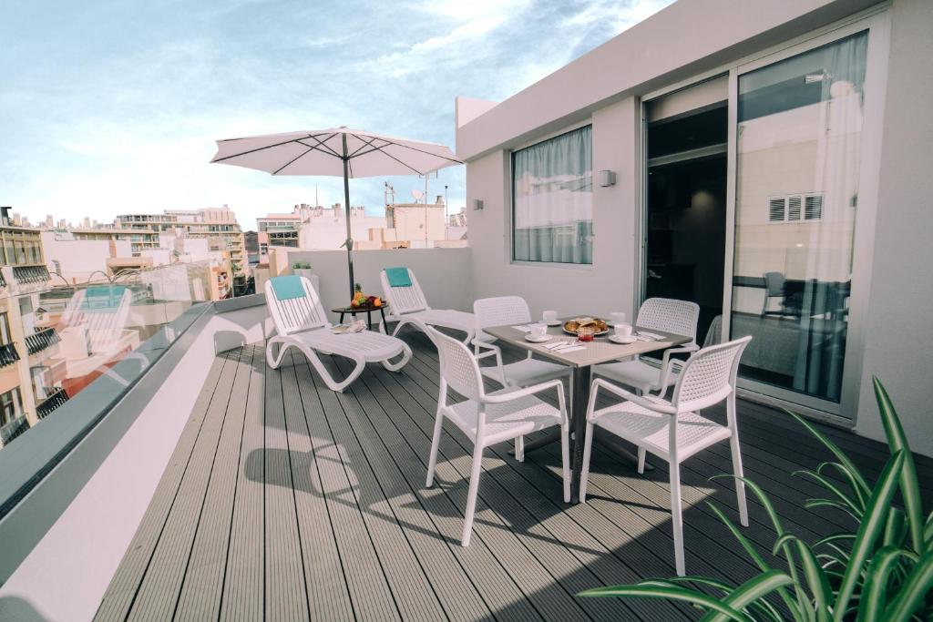 einen Balkon mit einem Tisch, Stühlen und einem Sonnenschirm in der Unterkunft Mannix Urban Apartments in Las Palmas de Gran Canaria