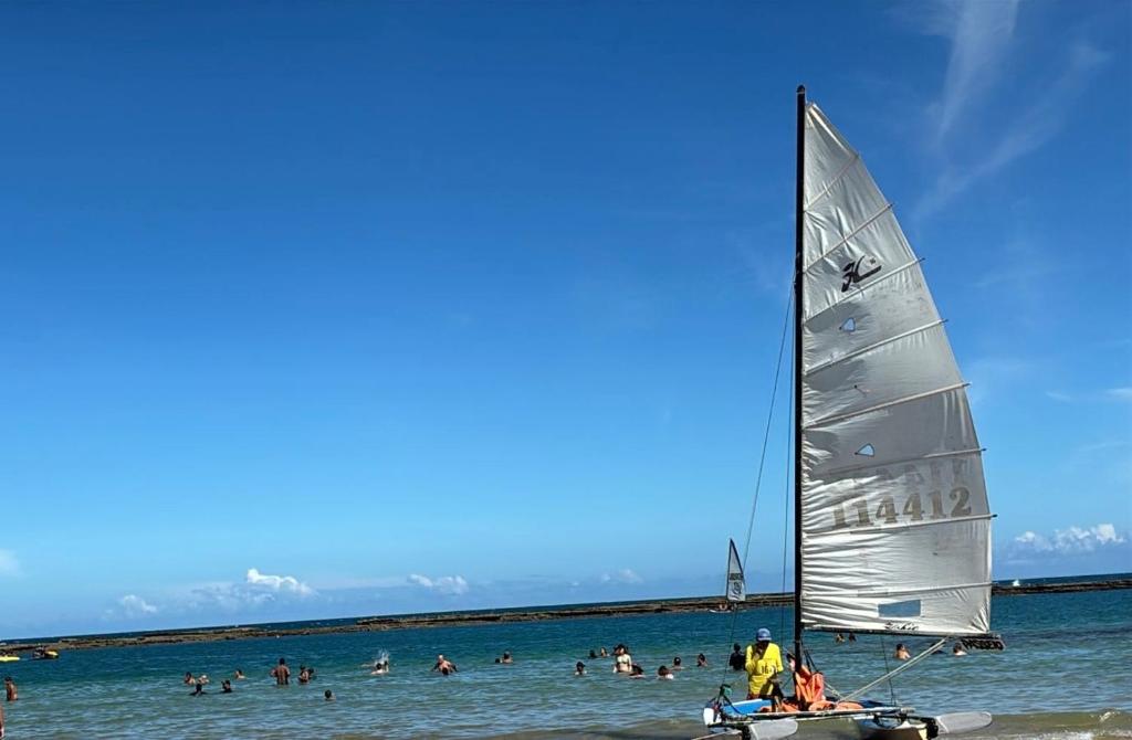 a sail boat on the beach with people in the water at Sol, mar, equilíbrio perfeito praia do frances! in Marechal Deodoro