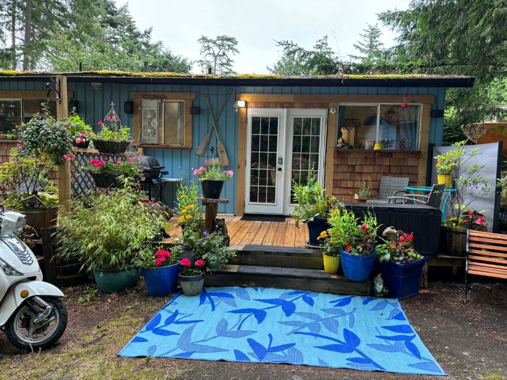 a tiny house with a porch with potted plants at Sea 'N' Stars BNB in Gabriola