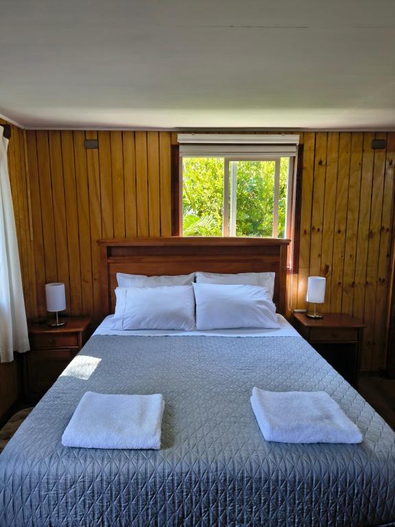 a bedroom with a bed with two towels on it at Cabañas CyG - Chaitén in Chaitén
