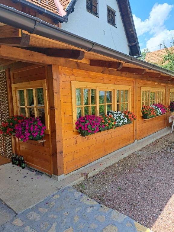 a wooden house with windows with flowers on it at Domacinstvo Majovac in Drenova