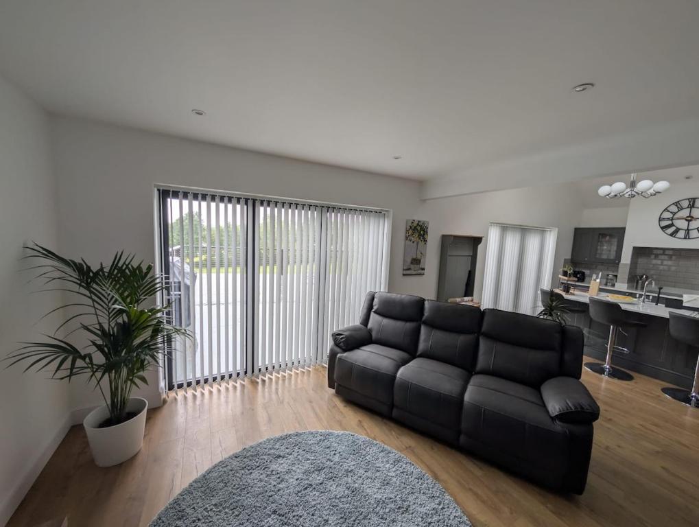 a living room with a black couch and a kitchen at Allensmore House Gower in Swansea