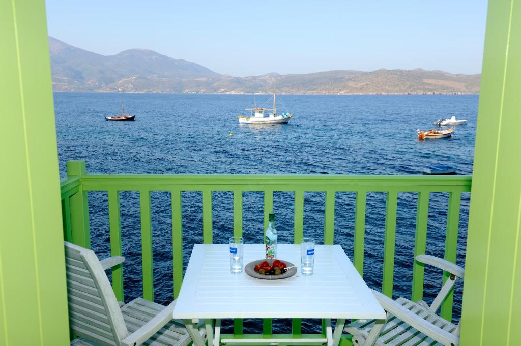 a table and chairs on a balcony with the water at Tsakanos Traditional Sirma in Klima