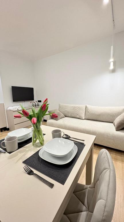 ein Wohnzimmer mit einem Tisch mit Tellern und Blumen darauf in der Unterkunft Studio 39 in Płock