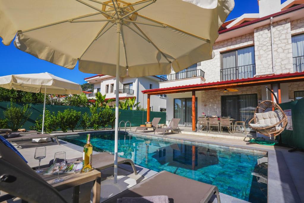 a swimming pool with an umbrella next to a house at Villa Karya in Dalyan