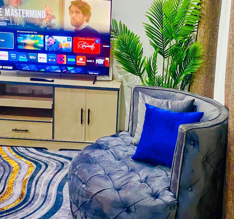 a couch with a blue pillow in front of a tv at 7th Heaven luxury Apartment in Gaborone
