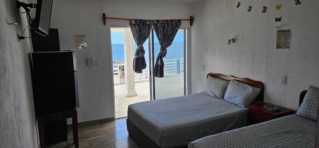 a bedroom with a bed and a sliding glass door at Posada "Las Palmeras" in Dzilam de Bravo