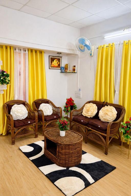 a living room with couches and a table and yellow curtains at Elite Hostel- SB Road Pune in Pune
