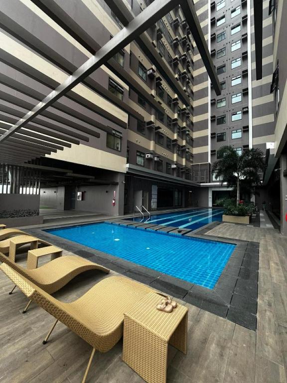 a large swimming pool in a building with some chairs at Aurora Escalades Residences in Manila