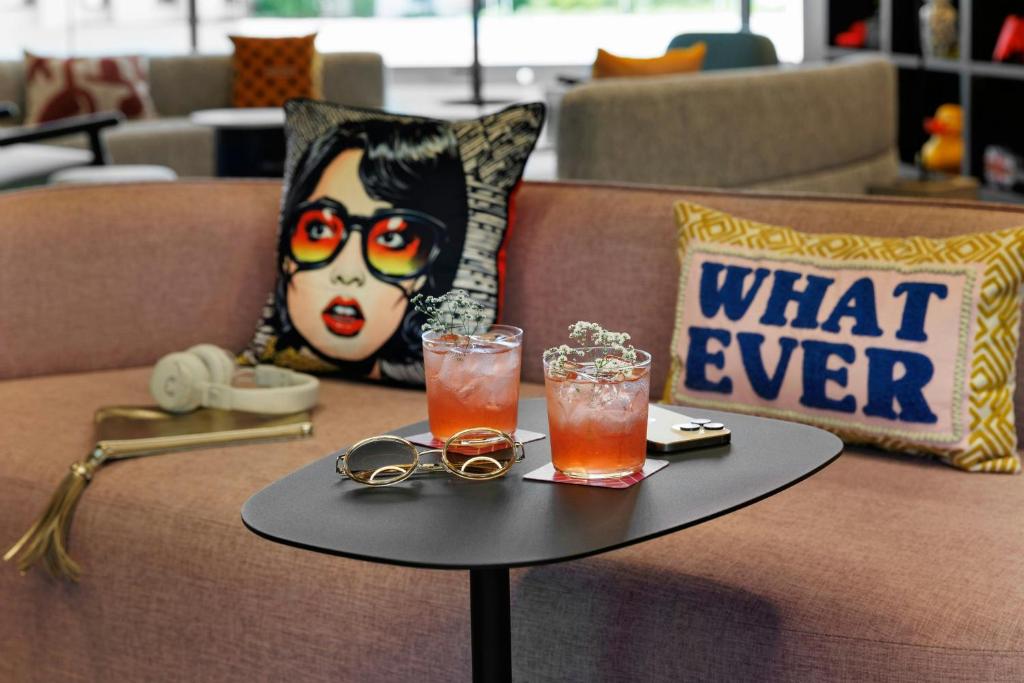 A close-up lounge vignette pairs two pink drinks with playful cushions on a sofa.