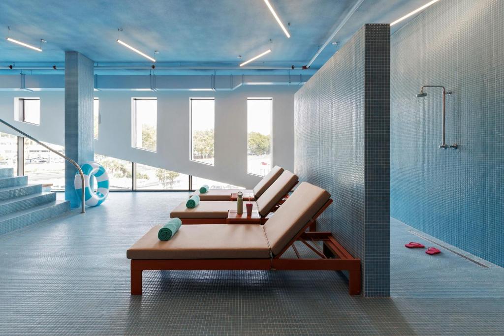 A bright tiled leisure area with loungers and an open shower.