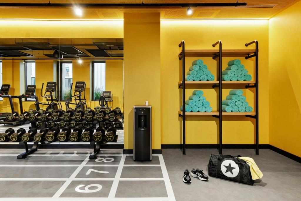 A gym corner with dumbbells, treadmills, drinking water and towel shelving.