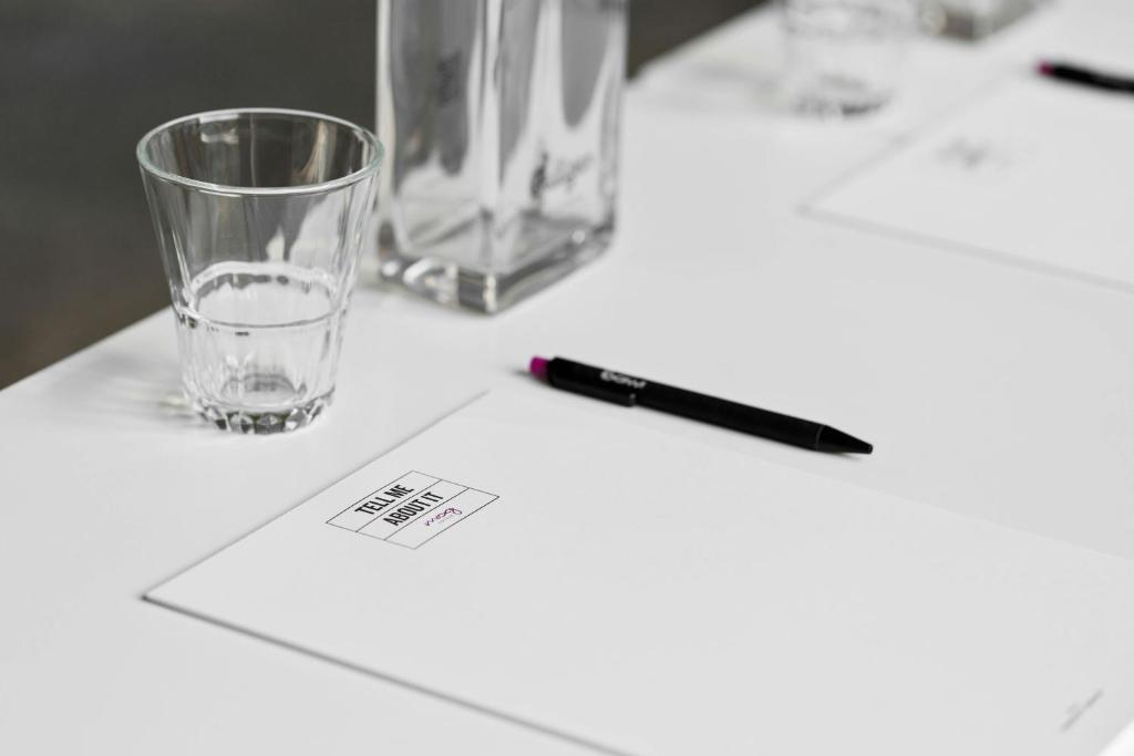 A prepared meeting table with a glass, water carafe, pen and printed stationery.