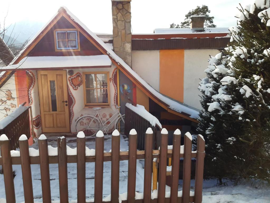 a small house with a fence in the snow at Perníčka in Leštiny