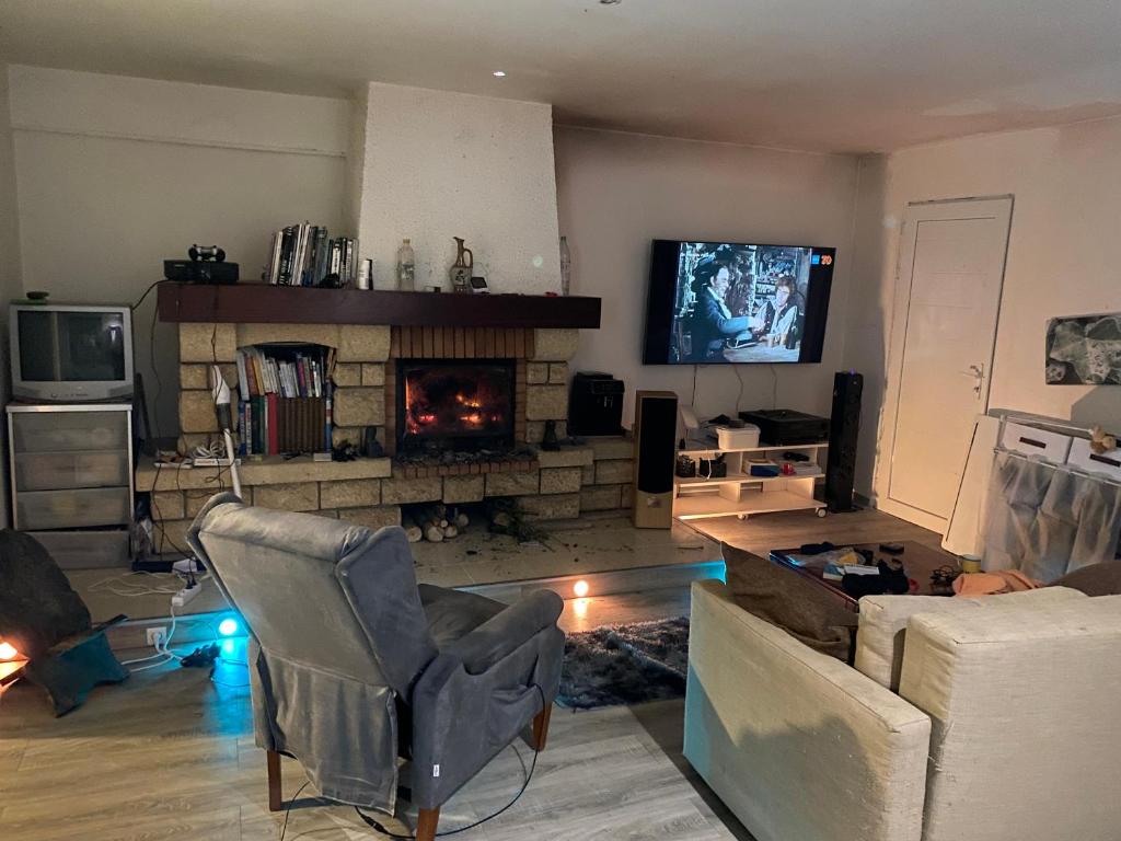 a living room with a fireplace and a tv at Maison de Campagne in Aussonne