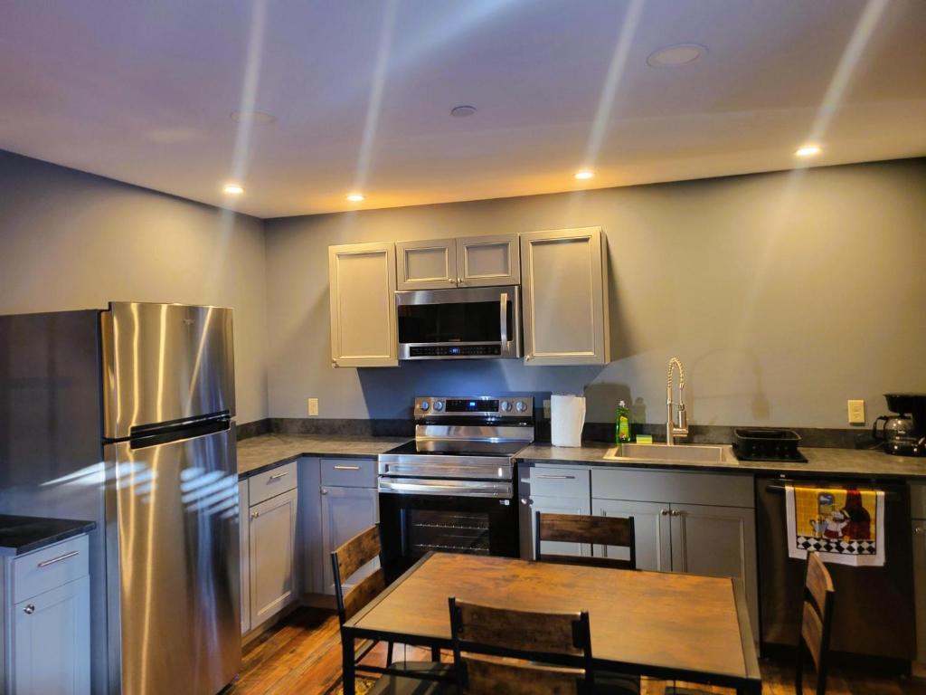 a kitchen with stainless steel appliances and a wooden table at Cold Brook Lodge - 2 and 3 Bedroom Luxury Apartments in Lake Placid