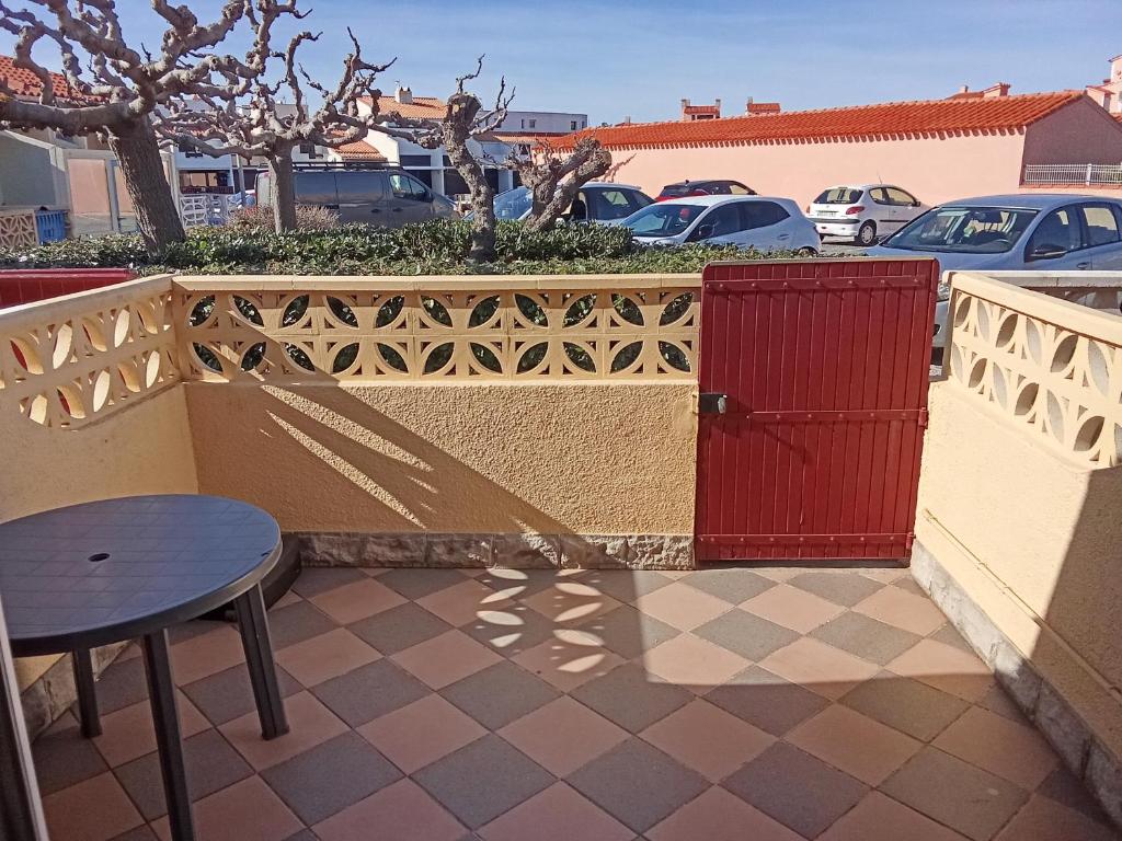 a red door on a fence with a table at Maison cosy Santa Barbara in Le Barcarès